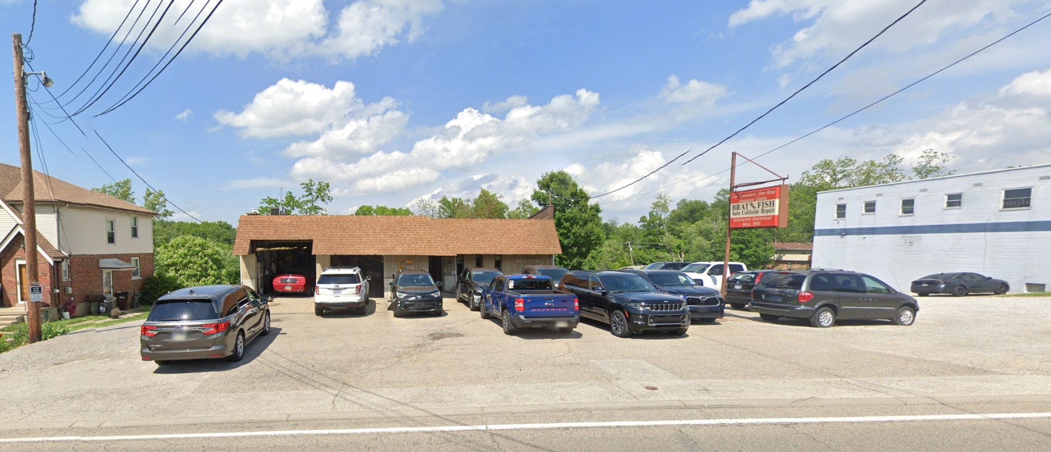Exterior of Bratfish Auto Collision Repair Inc., showing the shop, parking lot and roadside sign on Blue Rock Road